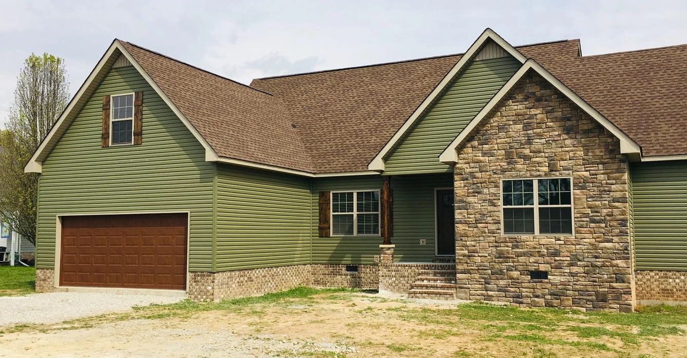 Completed home exterior with green siding and stone accents